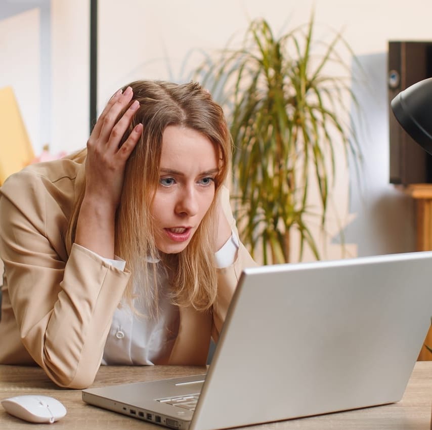 frustrated woman working on a laptop with her head in her hands